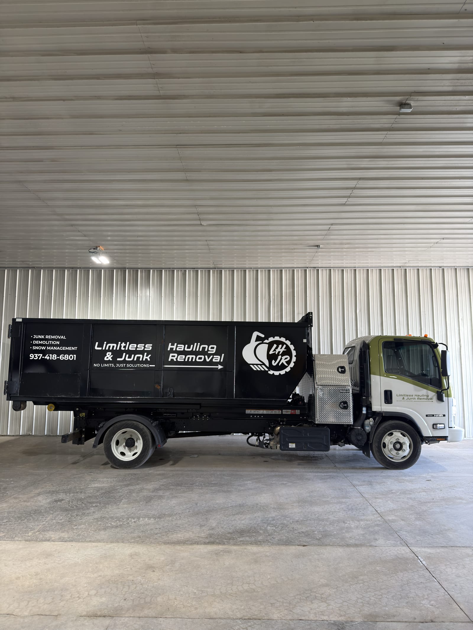 A branded Limitless Hauling dump truck parked in the company shop
