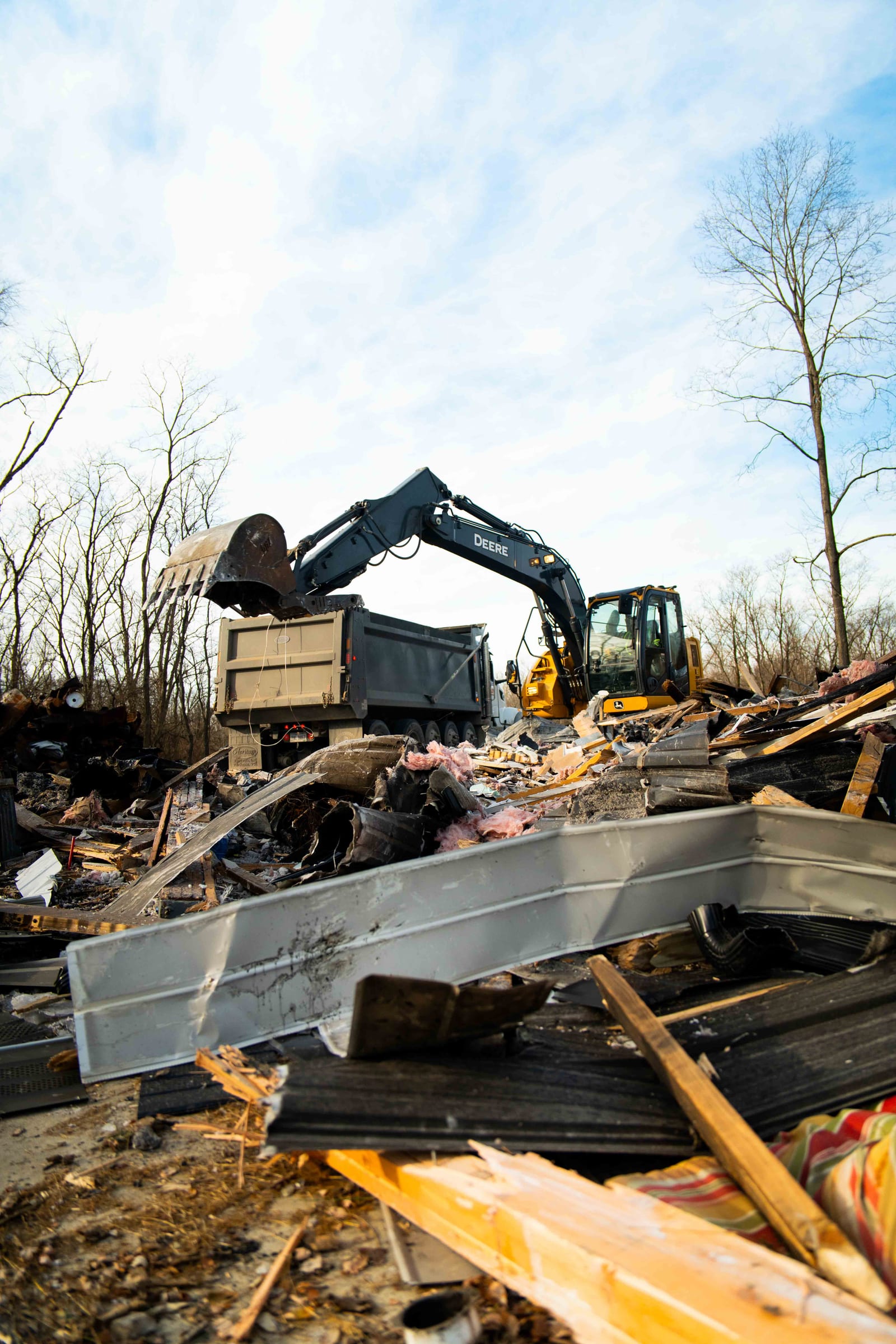 A Limitless excavator loading demolition debris into a dump truck on a cleared lot