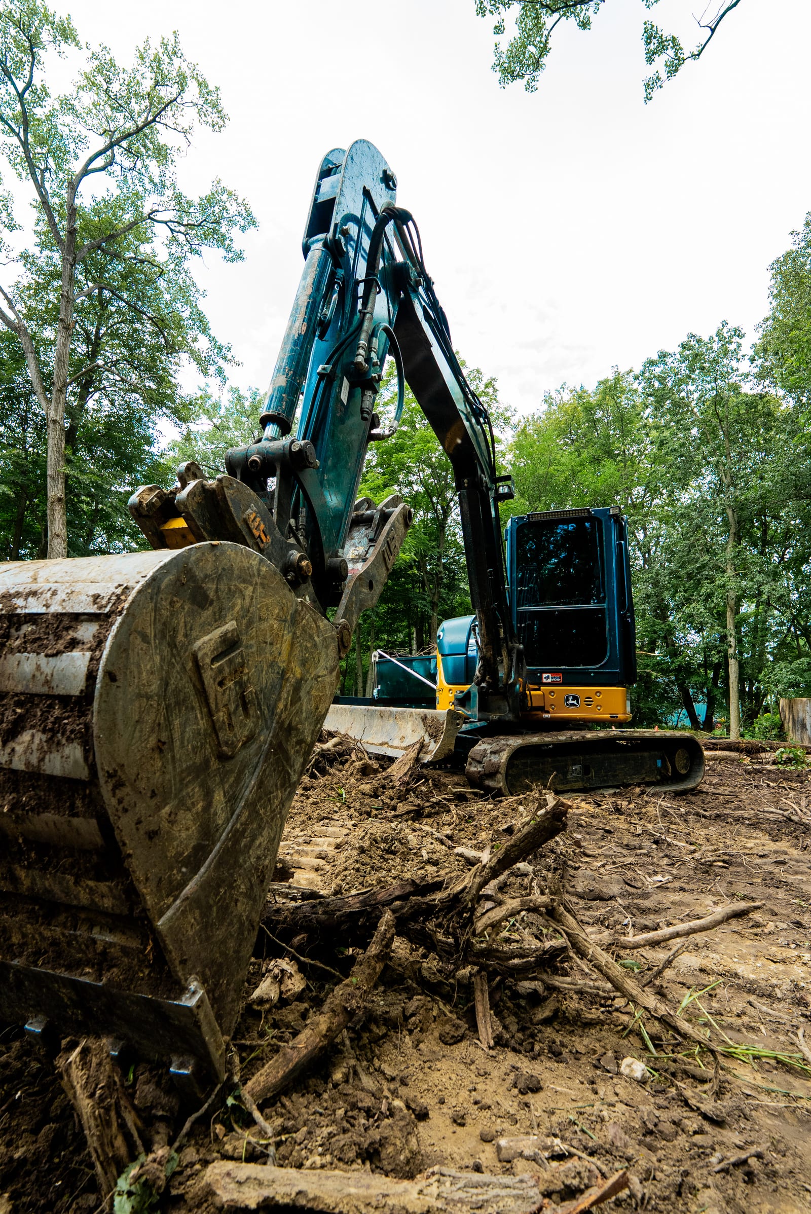 An excavator lifting a large tree trunk during a land clearing job